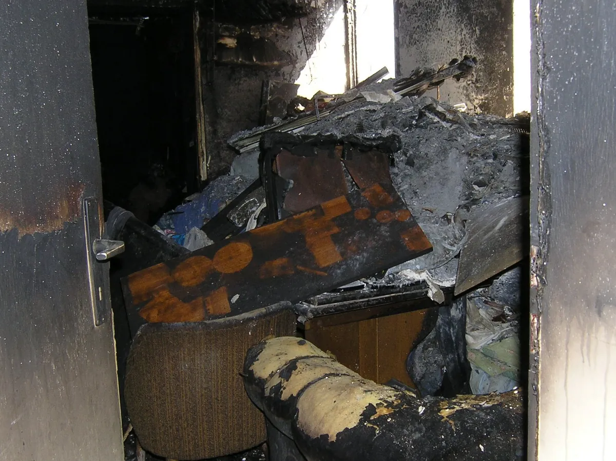 Ausgebranntes Zimmer mit verkohlten Möbeln und rußgeschwärzten Wänden
