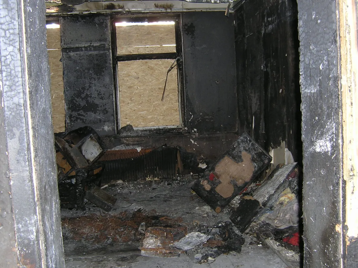 Vom Brand geschädigter Raum mit ausgebrannten Fensterrahmen vor dem Rückbau