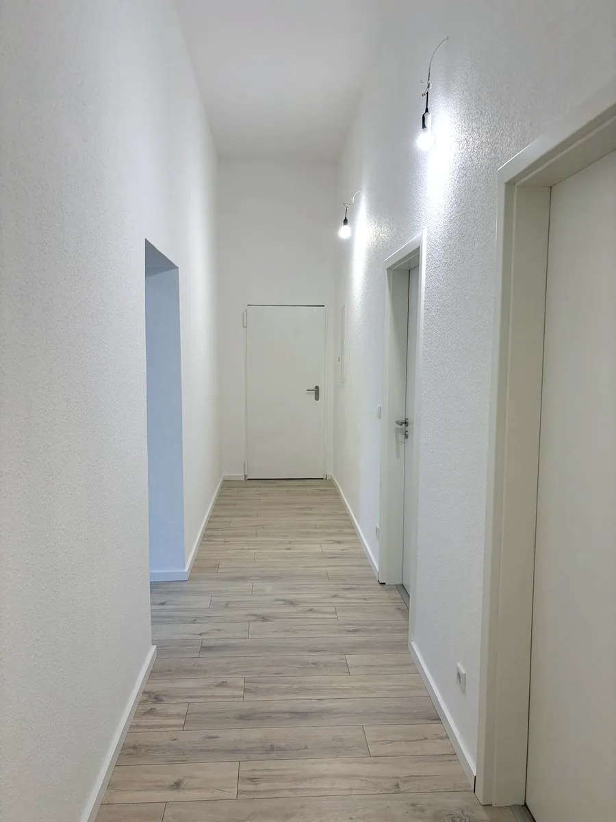 Renovierter Flur mit neuem Boden in Holzoptik und weißen Türen